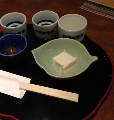 A final sake samplier with a small bite of tofu.